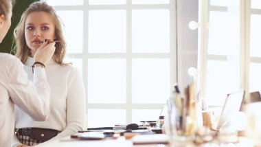 Makyaj sanatçısı genç ve güzel gelinin makyajını yapıyor.