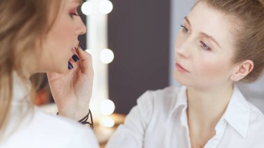 Makyaj sanatçısı genç ve güzel gelinin makyajını yapıyor.