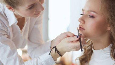 Güzel, genç bir model kadın makyaj yaptırıyor.