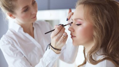 Güzel, genç bir model kadın makyaj yaptırıyor.