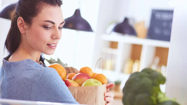 Mosolygó nő vesz egy friss gyümölcsöt ki a hűtőből, egészséges étel koncepció — Stock Fotó