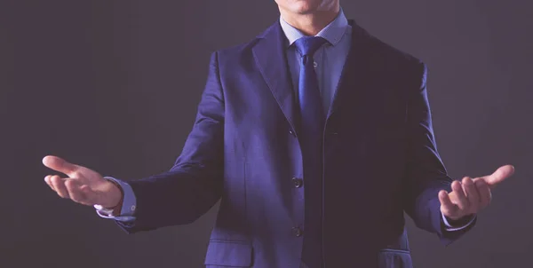 Retrato de un exitoso joven alegre y lindo que presenta un nuevo producto, mostrando un espacio de copia en su palma sobre un fondo gris — Foto de Stock