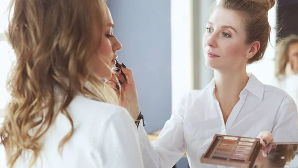 Maquiagem artista fazendo maquiagem para a noiva bonita jovem aplicando casamento make-up — Fotografia de Stock