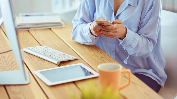 Ung affärskvinna sms när du sitter på kontoret framför laptop — Stockfoto