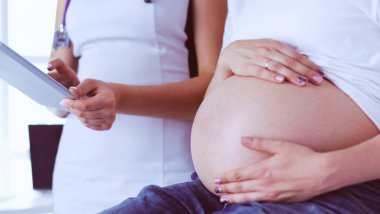 Genç bayan doktor klinikte hamile kadını muayene ediyor..