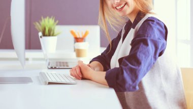 Ofis masasında çalışan ve dizüstü bilgisayarla yazan kendine güvenen genç bir iş kadını.