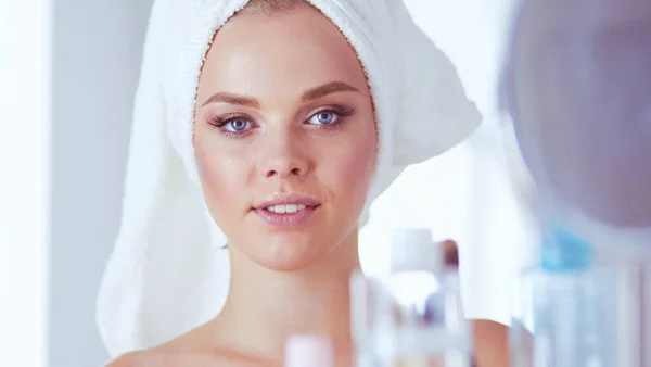 Giovane donna in accappatoio guardando nello specchio del bagno — Foto Stock