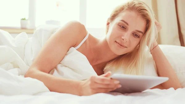 Meisje met digitale tablet met blanco scherm en glimlach op de camera in de slaapkamer — Stockfoto