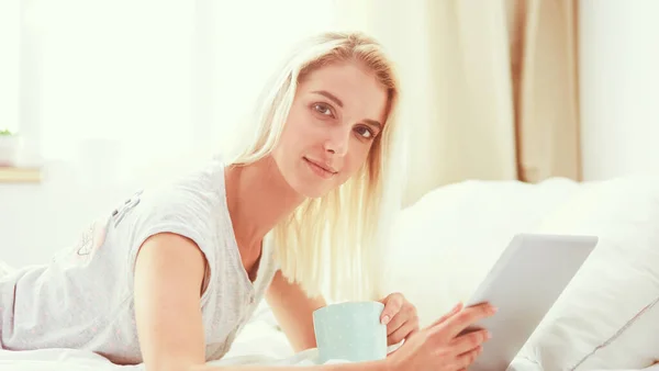 Chica sosteniendo tableta digital con pantalla en blanco y sonriendo a la cámara en el dormitorio — Foto de Stock