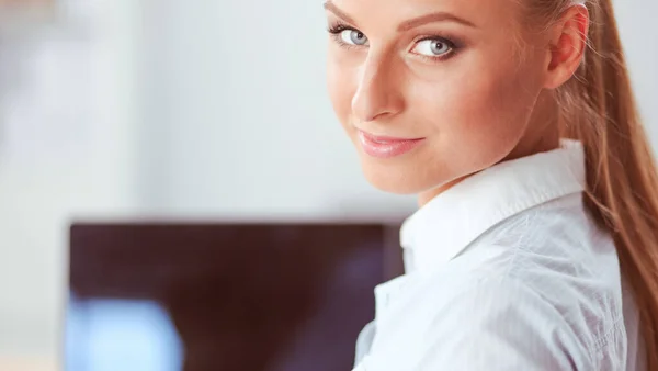Portret van een lachende receptioniste met laptop en headset op kantoor — Stockfoto