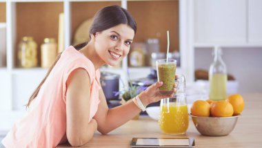 Mutfakta dijital tablet kullanan güzel genç bir kadın.