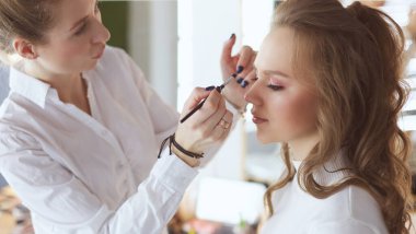 Güzel, genç bir model kadın makyaj yaptırıyor.