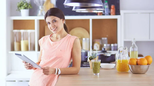 Schöne junge Frau mit einem digitalen Tablet in der Küche — Stockfoto