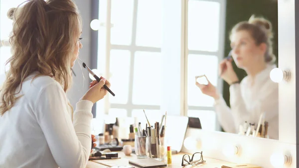 Make-up artist tillämpa vit ögonskugga i hörnet av modeller öga och hålla ett skal med ögonskugga på bakgrunden — Stockfoto