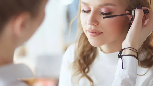 Young beautiful bride applying wedding make-up by professional make-up artist — Stock Photo, Image