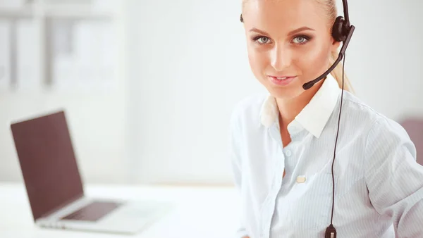 Portret van een lachende receptioniste met laptop en headset op kantoor — Stockfoto