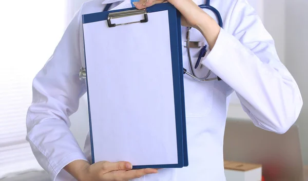 Médica sorridente com uma pasta em pé uniforme — Fotografia de Stock