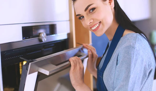 Mulher bonita verificando como seu bolo está indo no forno — Fotografia de Stock