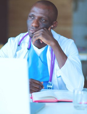 Masada dizüstü bilgisayarla çalışan genç bir Afrikalı doktor. Doktor bey. İşyeri