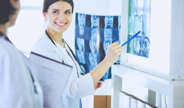 İki gülümseyen doktor hastane muayene odasında röntgenleri gösteriyor.