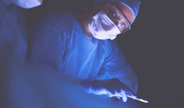 Equipe de médicos em cirurgia em um fundo escuro. — Fotografia de Stock