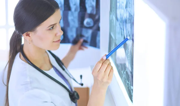 Giovane medico femminile sorridente con stetoscopio che punta ai raggi X presso lo studio medico — Foto Stock