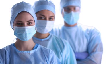 Cerrahlar, koruyucu üniformalar, kepler ve maskeler giyiyorlar.