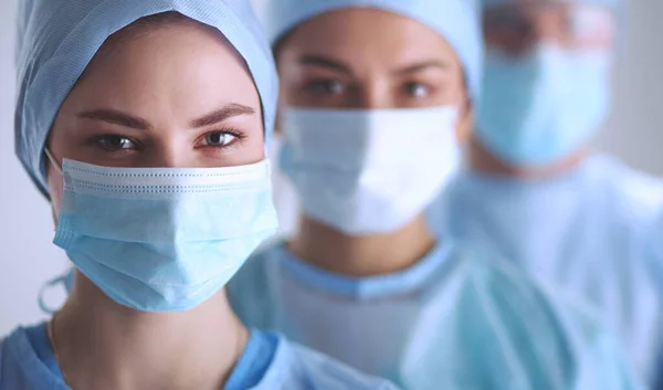 Squadra di chirurghi, indossando uniformi protettive, berretti e maschere — Foto Stock