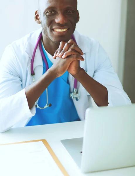 Retrato de un joven médico con auriculares mientras usa la computadora en el escritorio de la clínica. Doctor.. — Foto de Stock