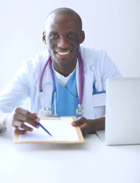 Portret van een jonge mannelijke arts die een headset draagt terwijl hij een computer gebruikt aan een bureau in de kliniek. Dokter.. — Stockfoto