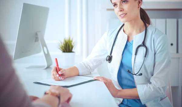 Médico y paciente discutiendo problemas médicos en una sala de consulta del hospital. Doc rellenando un formulario de pacientes — Foto de Stock