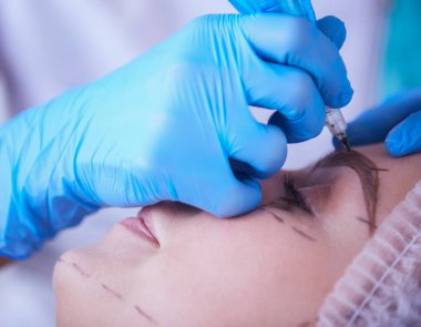 Kaşlar için kalıcı makyaj. Güzellik salonunda kalın kaşlı güzel bir kadın..