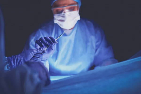 A műtétet végző orvos sötét háttérrel. — Stock Fotó