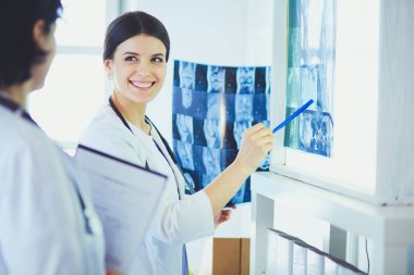 İki gülümseyen doktor hastane muayene odasında röntgenleri gösteriyor.