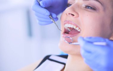 Dişçi muayenehanesinde diş muayenesi yapan ağzı açık genç bir kadın hasta..