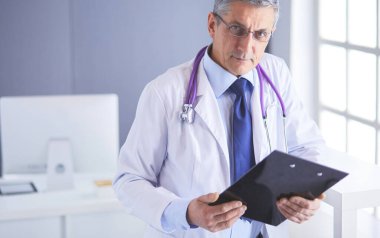 Erkek doktor hastanedeki panoya notlar yazıyor.