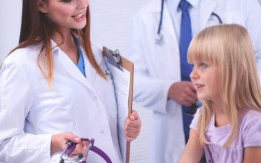 Kadın doktor ameliyatta steteskopla çocuğu muayene ediyor.