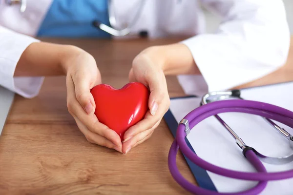 Kırmızı kalp sembollü genç doktor masasında tek başına oturuyor. — Stok fotoğraf