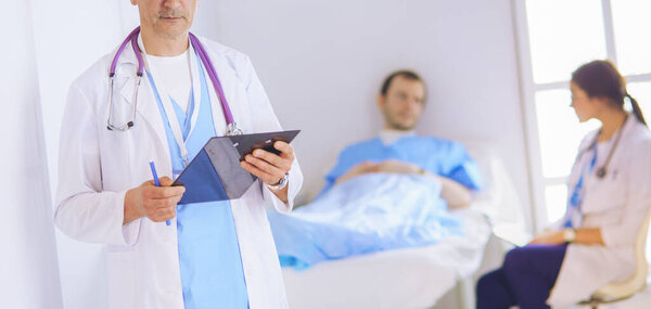 Doctor holding folder in front of a patient and a doctor
