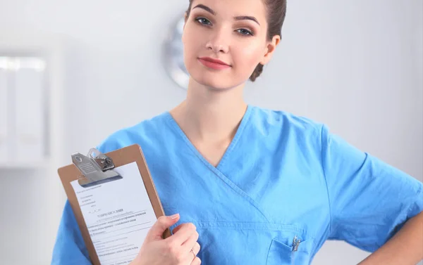 Médecin souriante avec un dossier en uniforme debout à l'hôpital — Photo