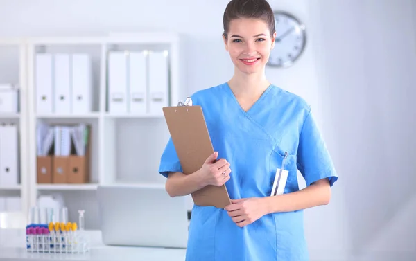 Leende kvinnlig läkare med en mapp i uniform stående på sjukhus — Stockfoto