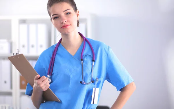 Médecin souriante avec un dossier en uniforme debout à l'hôpital — Photo