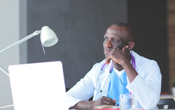 Un joven médico africano trabajando en un portátil en el escritorio. ¿Doctor? Lugar de trabajo — Foto de Stock