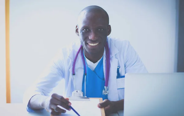 Porträtt av ung manlig läkare bär headset när du använder datorn vid skrivbordet på kliniken. Läkare. — Stockfoto