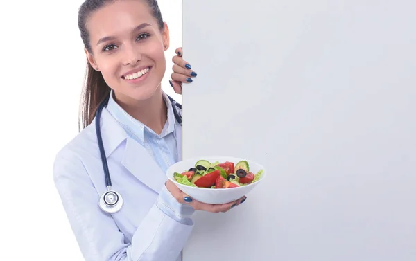 Retrato de una hermosa doctora sosteniendo un plato con verduras frescas en blanco. Mujeres doctores — Foto de Stock