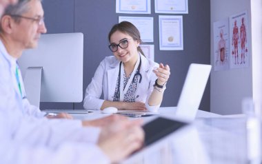 Ciddi bir tıbbi ekip parlak bir ofiste dizüstü bilgisayar kullanıyor.