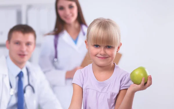 Child and medicine concept - female doctor giving an apple to smiling little girl — Stock Photo, Image