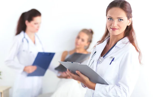 Médico sonriente con una carpeta en uniforme de pie en el hospital — Foto de Stock