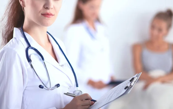 Sorridente medico donna con una cartella in uniforme in piedi in ospedale — Foto Stock