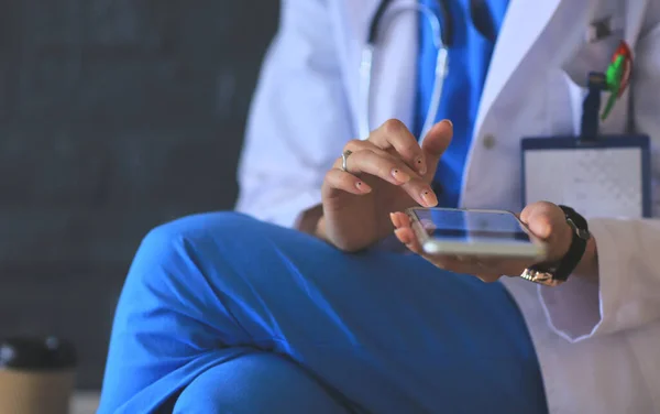 Jovem médico sentado com o seu telefone — Fotografia de Stock